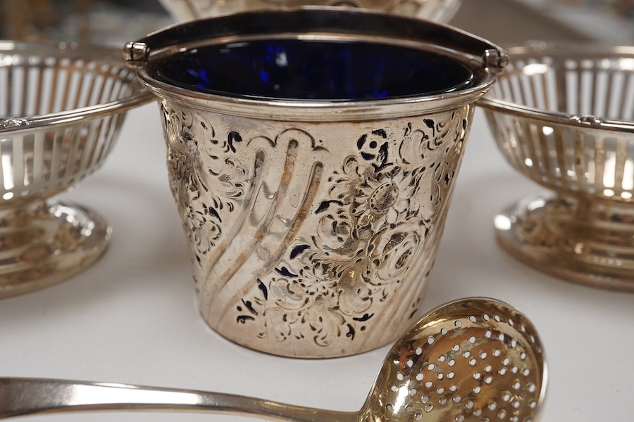 A George III small silver sugar basket, London, 1810, with blue glass liner, 57mm, a George III silver sifter spoon, a pair of silver bonbon dishes and an Edwardian small rose bowl, 16.9oz. Condition - poor to fair to go